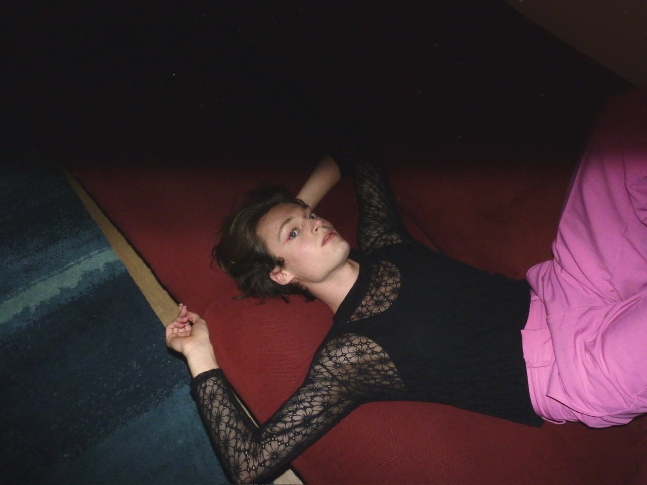 I’m on a red sofa, black sheer top, pink pants.
