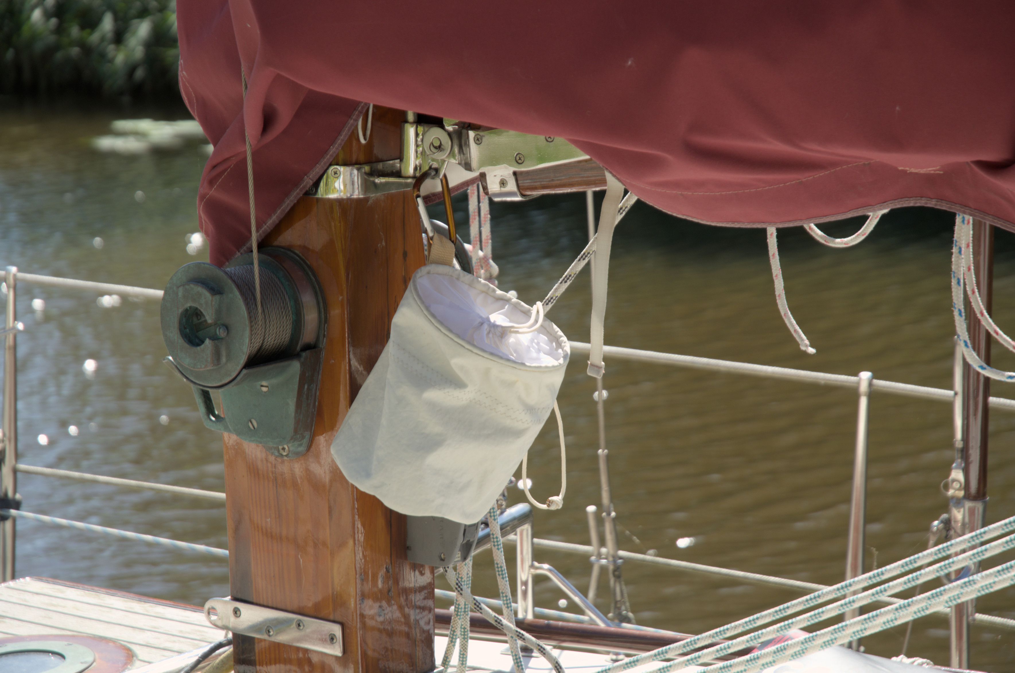 The pouch hanging under the boom. It is closed. The outside is a light grey sail material. The cover over the opening is a more white material.