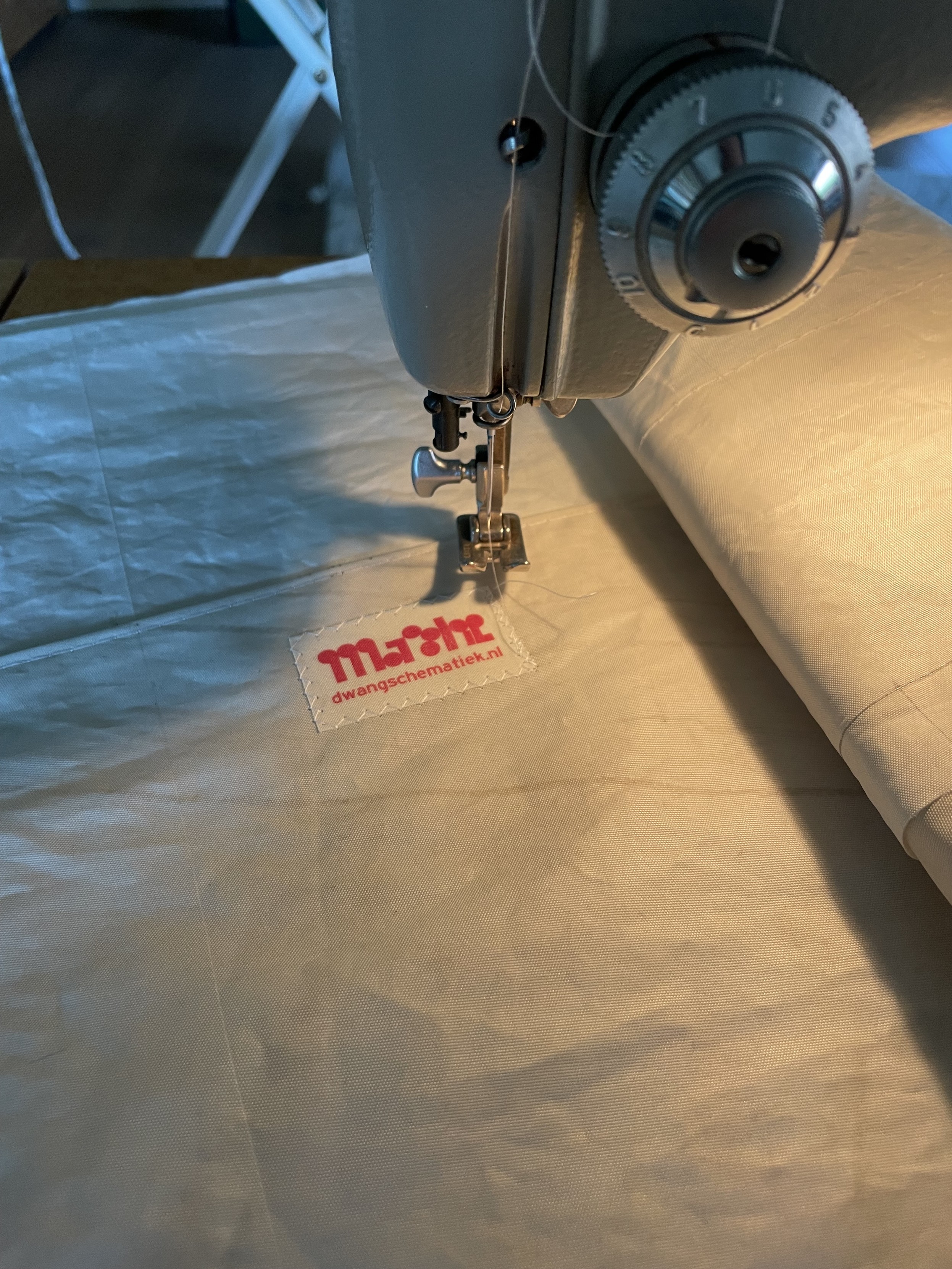 sewing in a red on white label onto a sailcloth bag