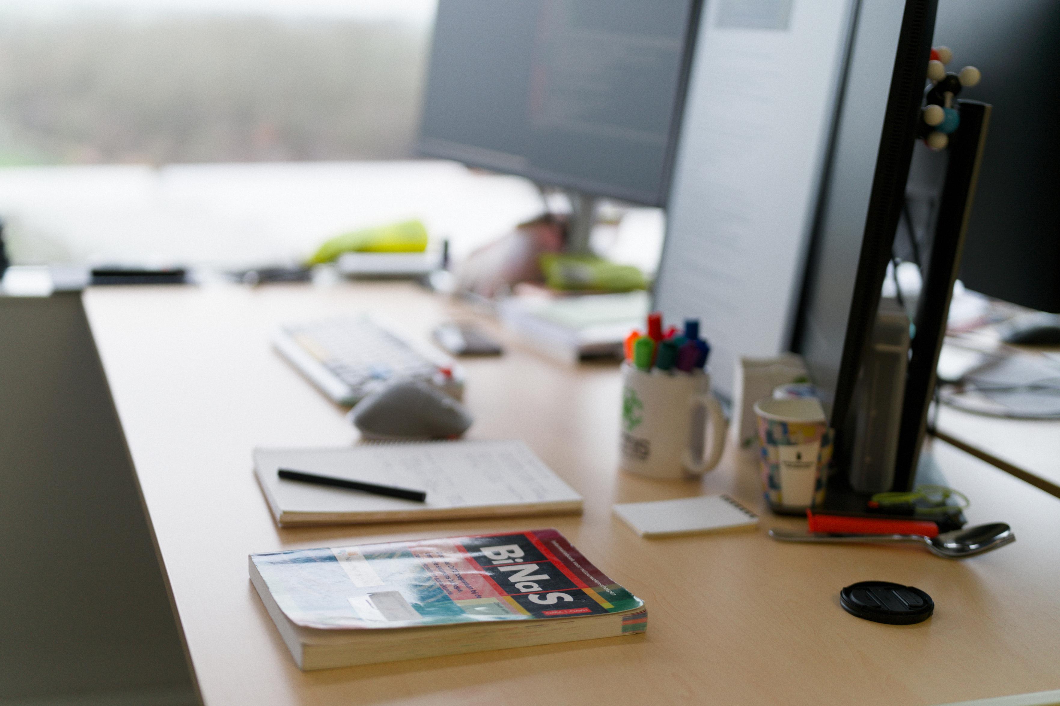 My desk with a book in the foreground with a colorful cover, titled 'BiNaS'.