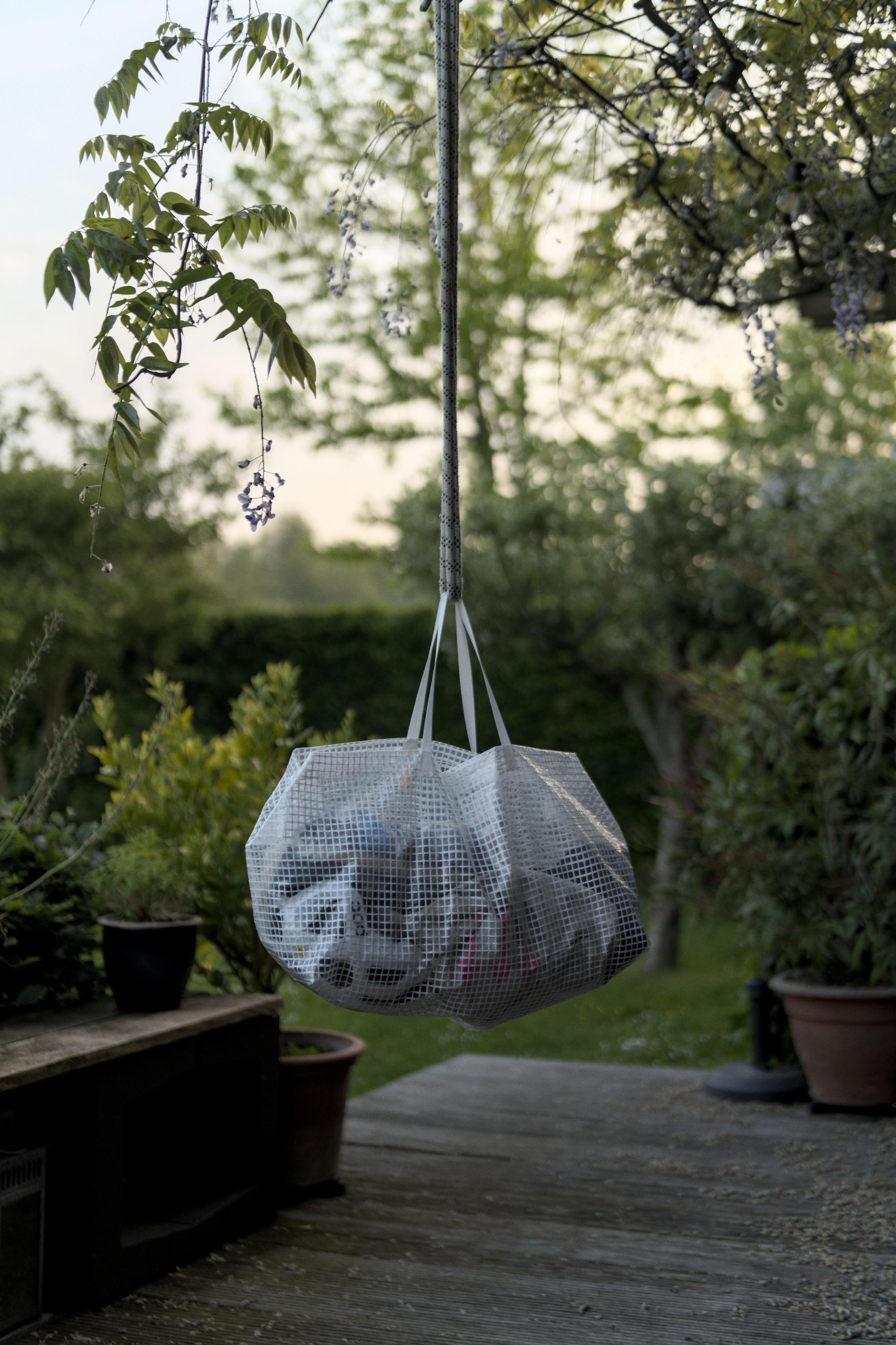 The bag hangs. Portrait crop. There is a soft
				 evening sky and the bag is in lower light but
				 still stands out from the garden background in an
				 interesting way.